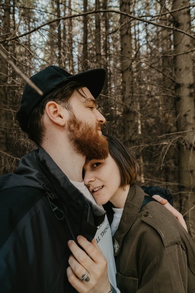 The man in black jacket to kiss a woman in a brown coat
